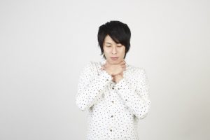 喉を押さえる男性