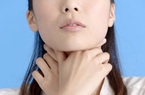 喉を押さえる女性