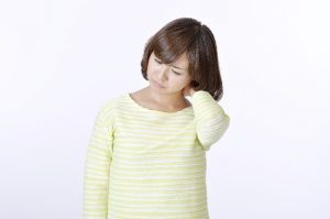 首の横に手をやる女性